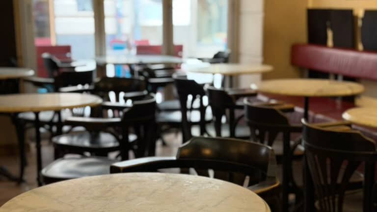 Nahaufnahme von Tische mit dunklen Holzstühlen in einem hellen Café.