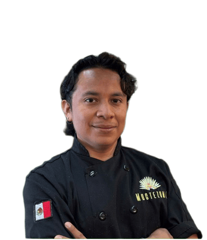 „Person in schwarzer Kochjacke mit verschränkten Armen.“